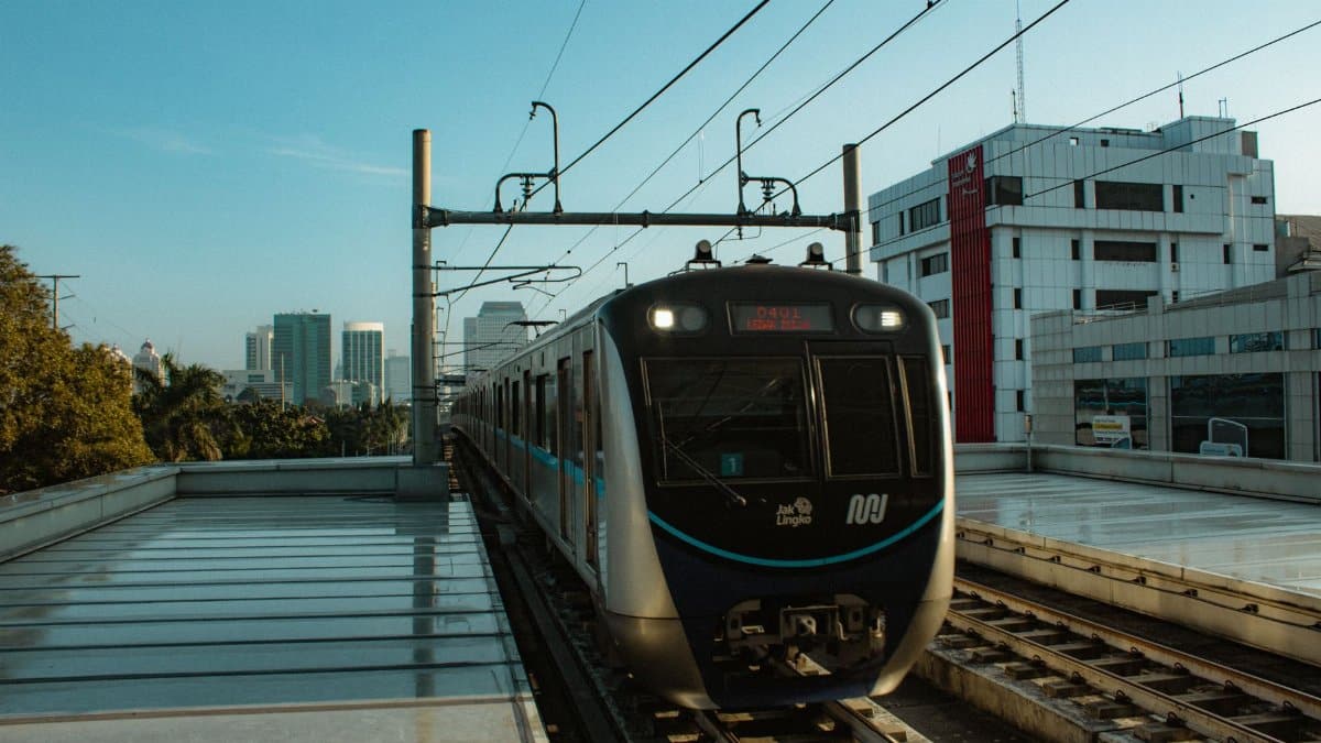 View of a modern metro train on an elevated track in Jakarta, Indonesia, with city skyline in the background.