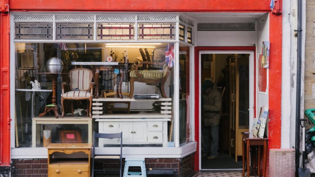 A charming storefront with vintage furniture and shop window on a city sidewalk.