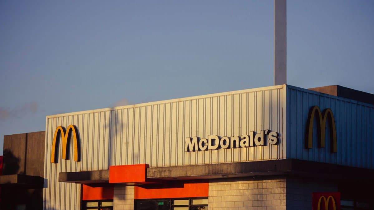 Photo of a McDonald's restaurant exterior under a clear sky, emphasizing its iconic architecture.