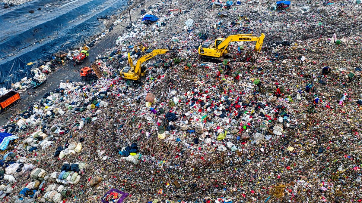 Aerial shot of a landfill in West Java with excavators and piles of trash, highlighting environmental issues.