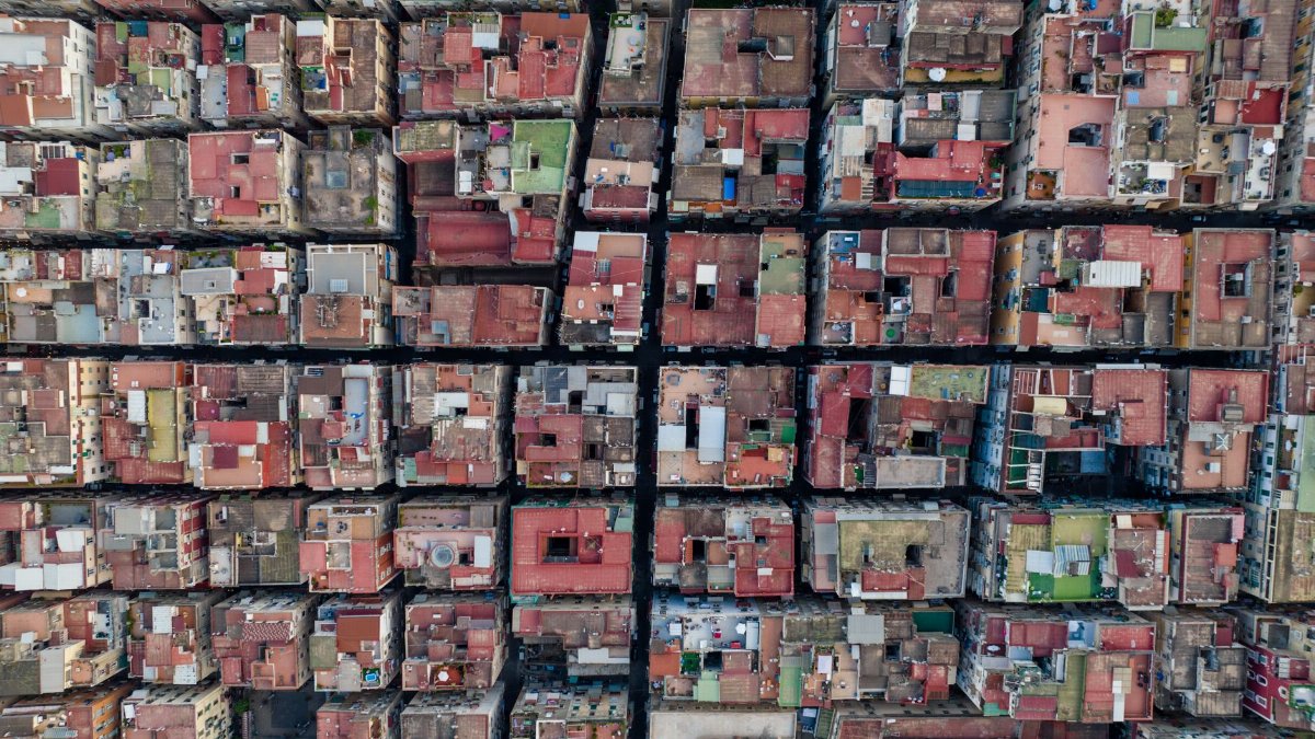 Drone shot capturing grid pattern of colorful urban rooftops and streets.