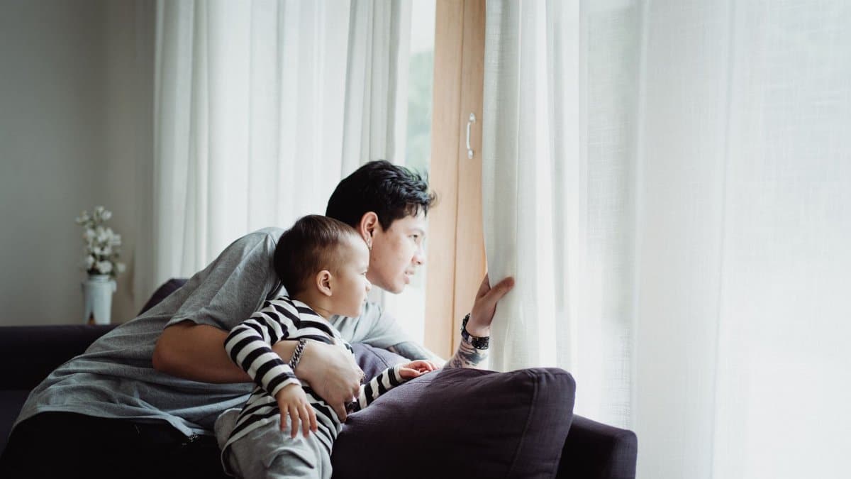 Father and son looking out the window together, capturing a serene family moment indoors.