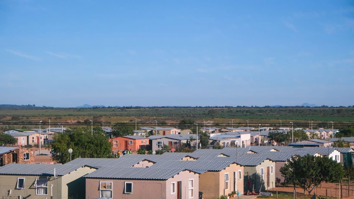 Aerial view showing concrete houses in a peaceful small town under a clear blue sky.