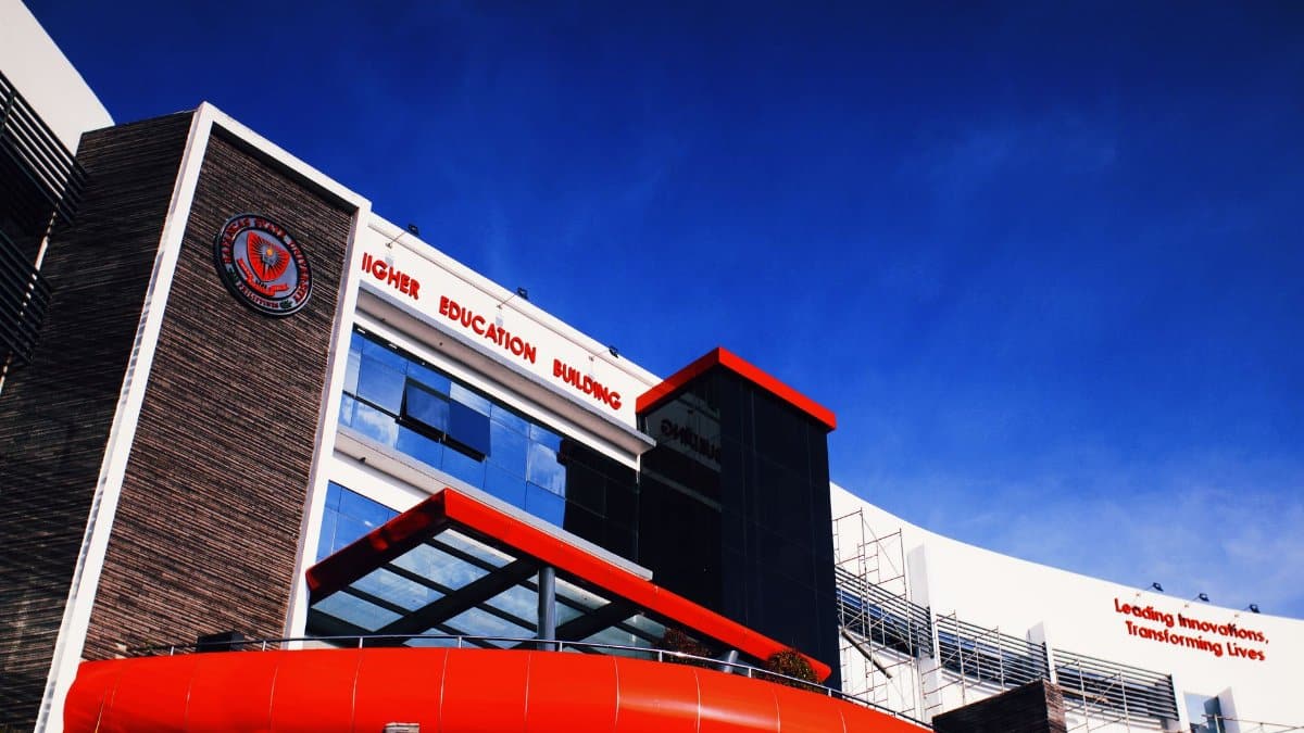 Low angle shot of a modern university building facade under a clear blue sky.