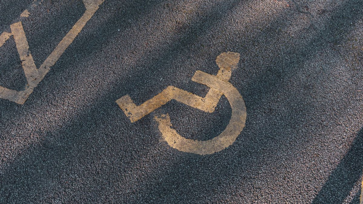 Close-up of an asphalt parking spot with a yellow wheelchair symbol for accessibility.