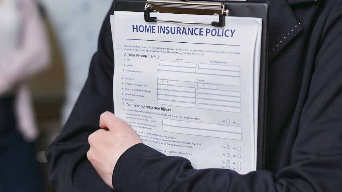 Close-up of a person holding a home insurance policy on a clipboard, captured indoors.