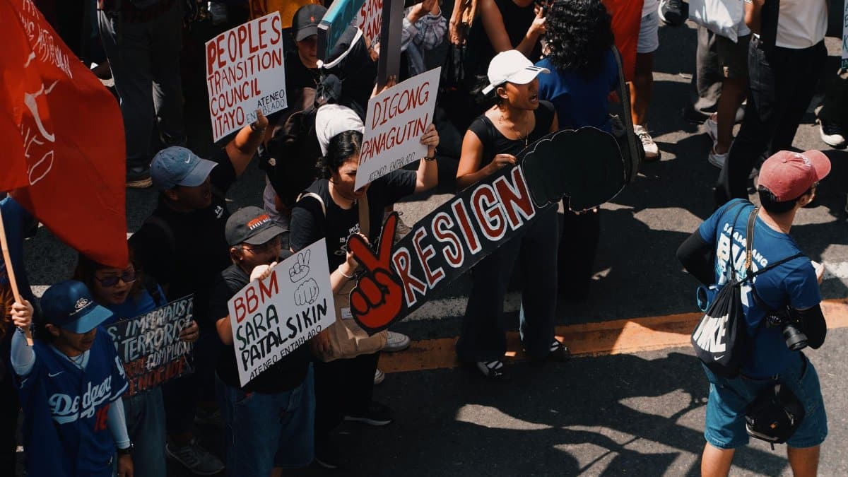 People rallying in urban protest with signs calling for political change.