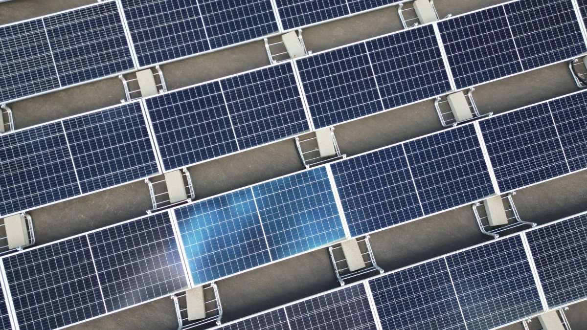 Aerial view of a large array of solar panels on a rooftop, utilizing renewable energy.