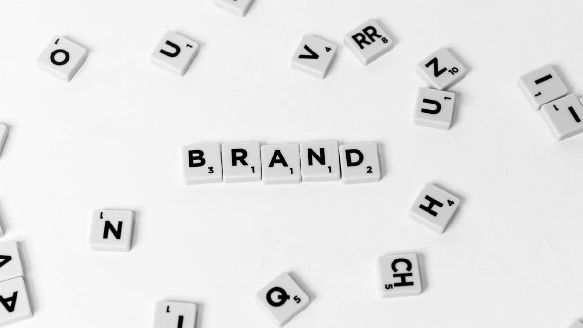 A flat lay of scattered letter tiles forming the word 'BRAND' on a white background.