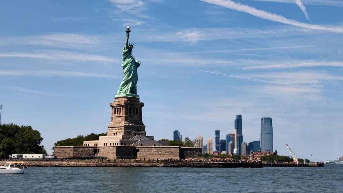 Iconic Statue of Liberty set against the New York City skyline on a clear day.
