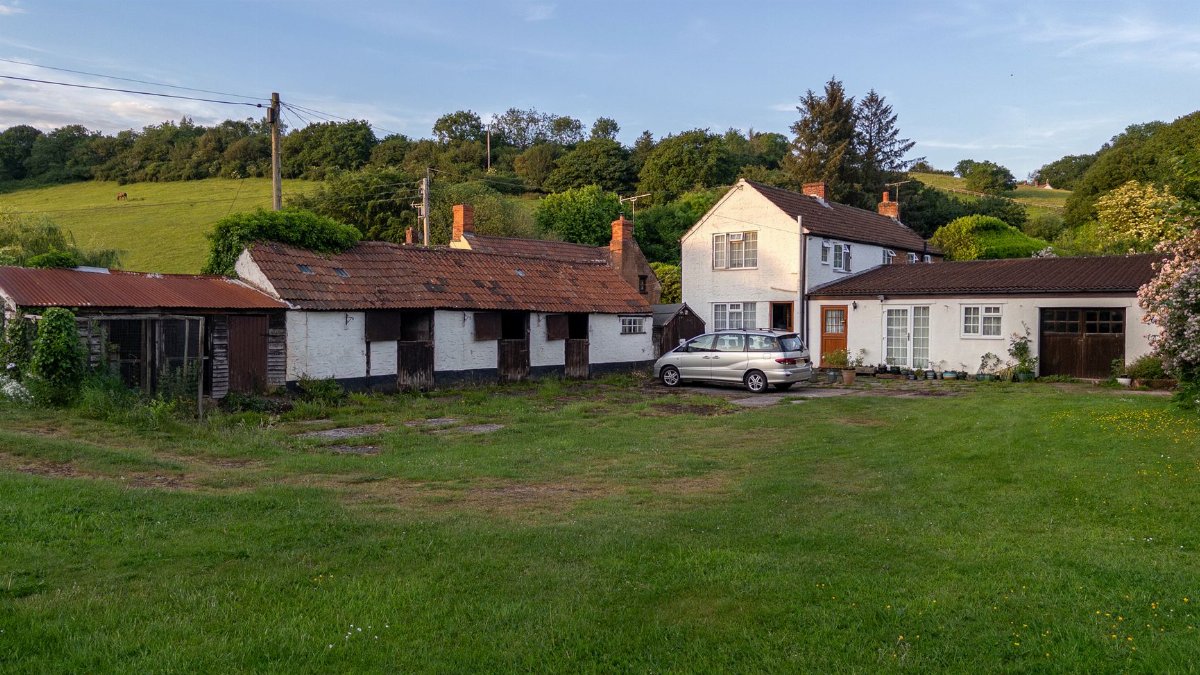 Idyllic farmhouse scene in Merridge, Somerset with lush greenery and evening light.