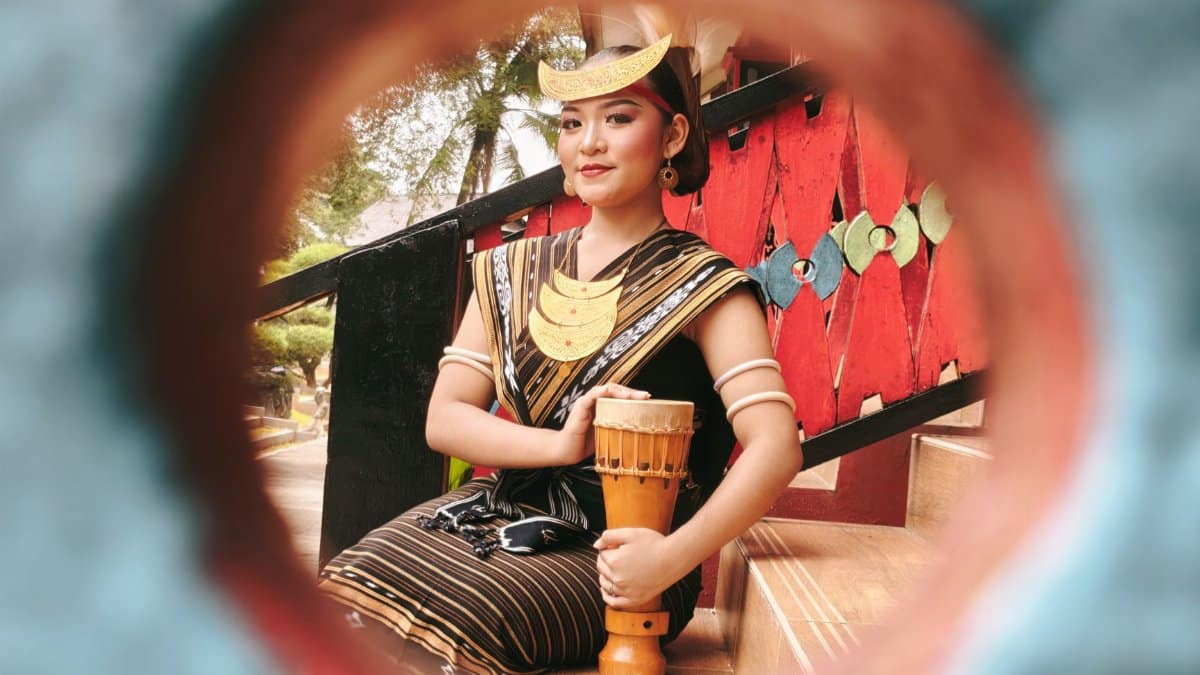 Portrait of a woman in cultural dress with a drum, framed creatively.