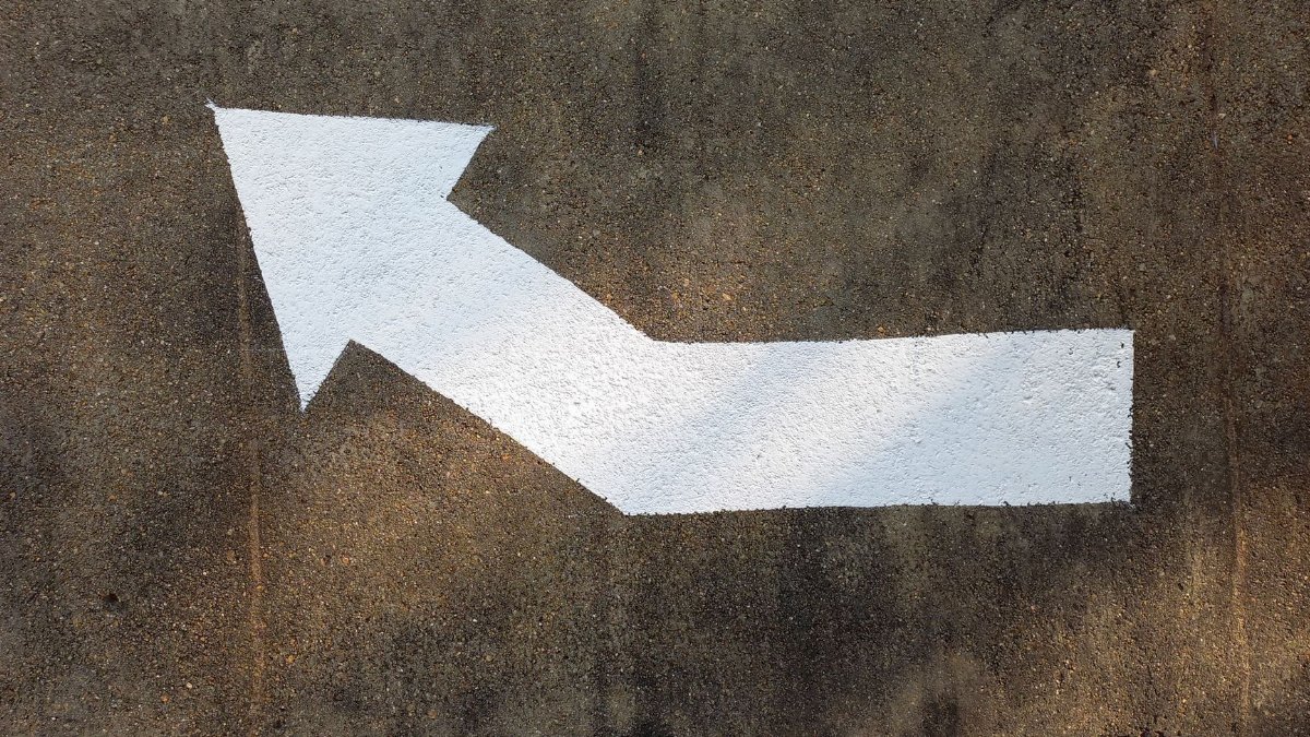 White painted arrow on concrete pavement indicating direction.