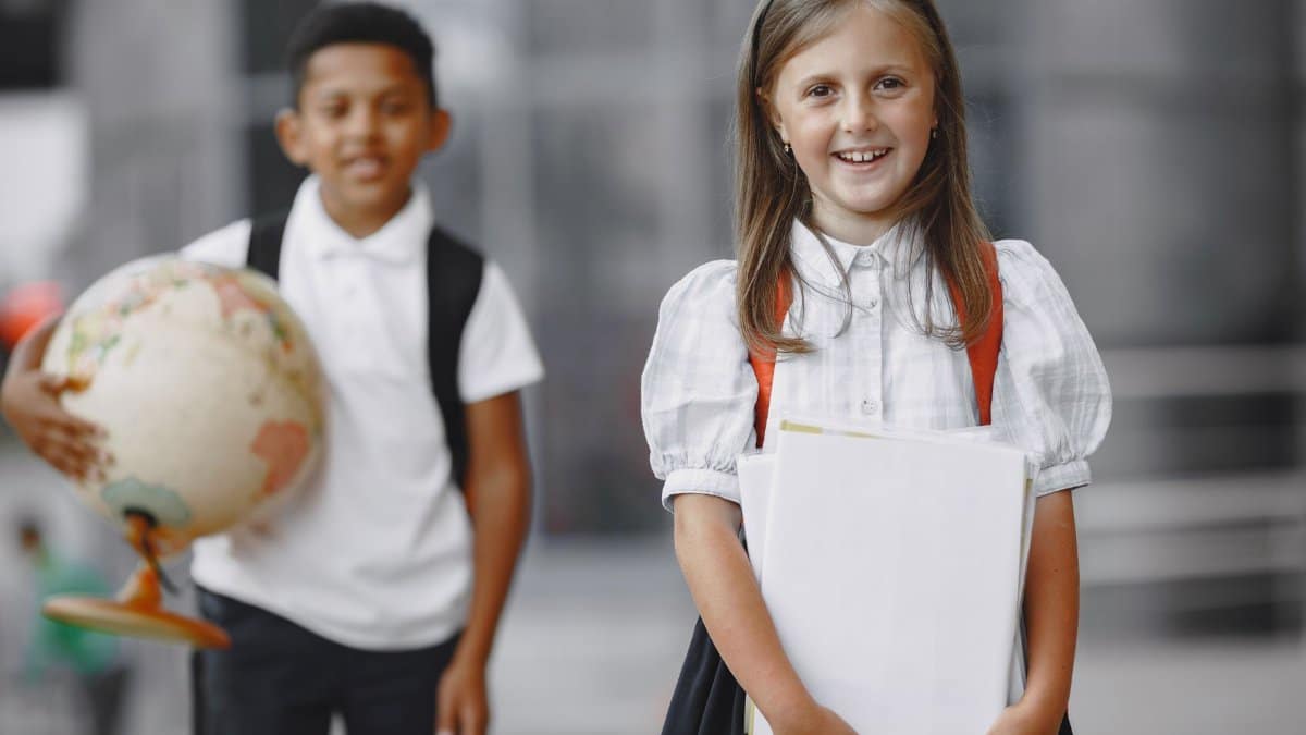 Happy students in school uniforms with books and globe, ready for learning adventures.