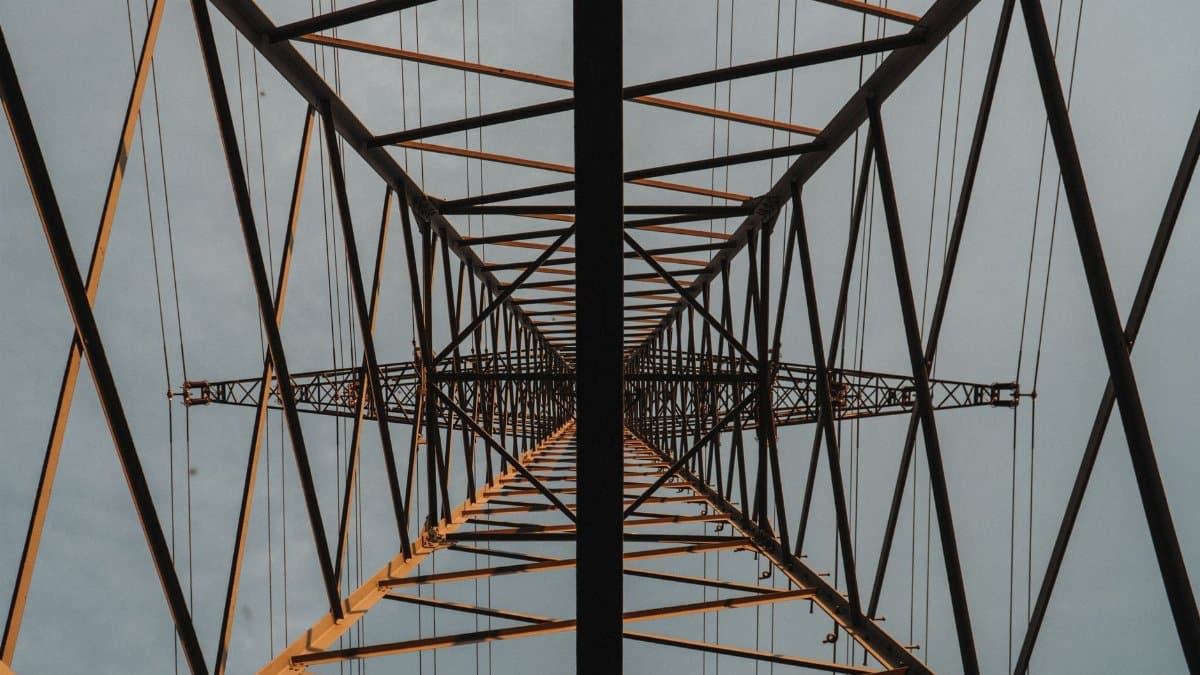 Looking up through a lattice structure of a towering metal construction against the sky.