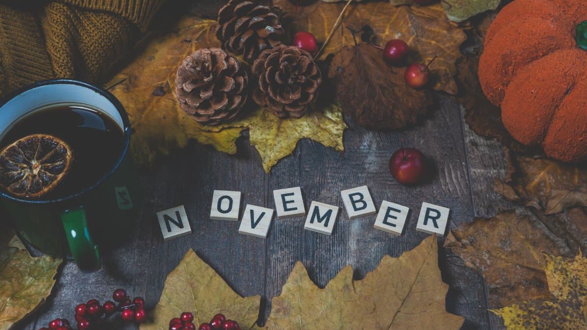 A warm autumn scene featuring a hot drink, leaves, and November-themed decor.