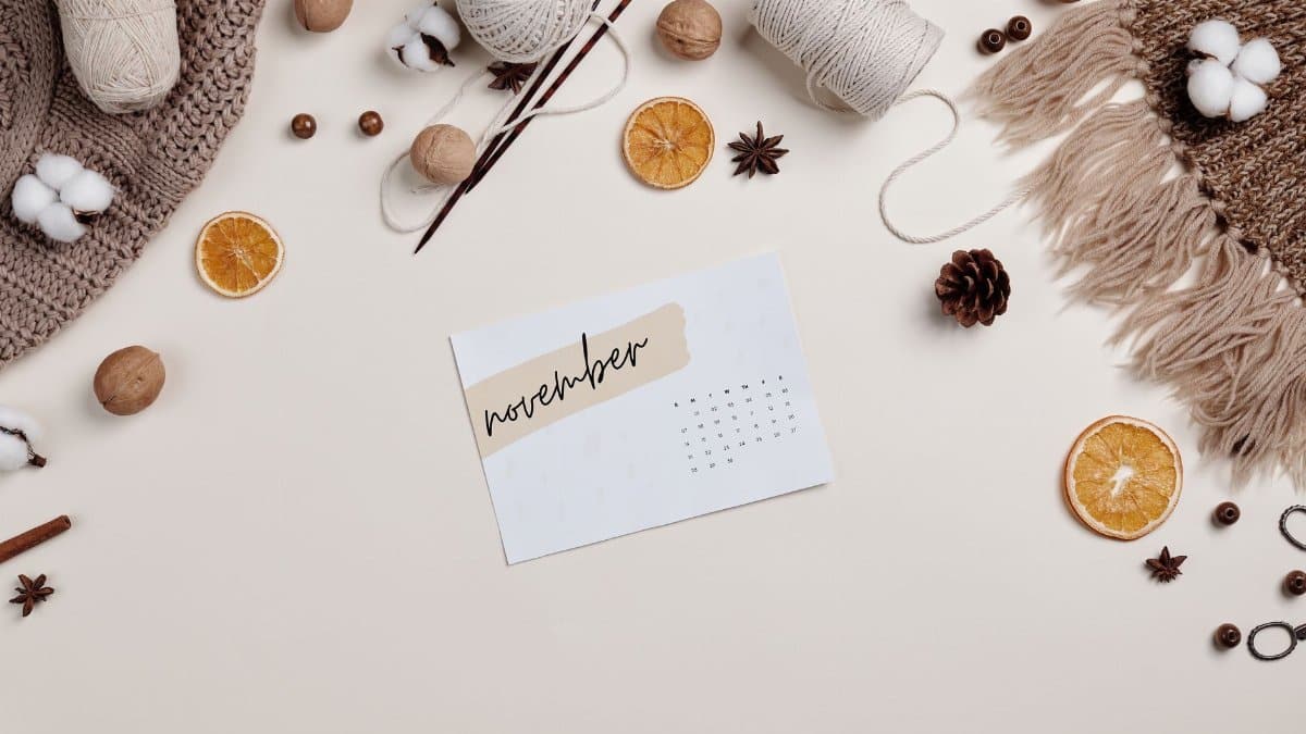 Flat lay of a cozy autumn setup with a November calendar, yarn, and dried oranges.