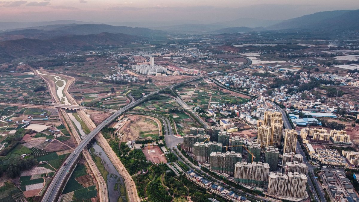 Drone view scenery of contemporary city district located near rough picturesque hills and narrow river