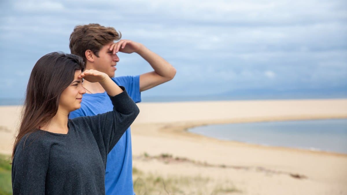 Two young adults looking out at the ocean on a cloudy day at the beach in Portugal.