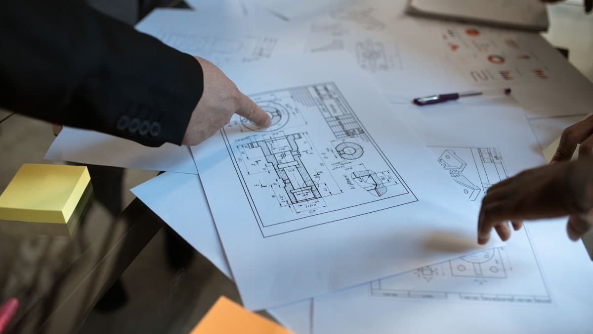 Engineers discussing blueprints at a workspace, focusing on teamwork and architecture design.