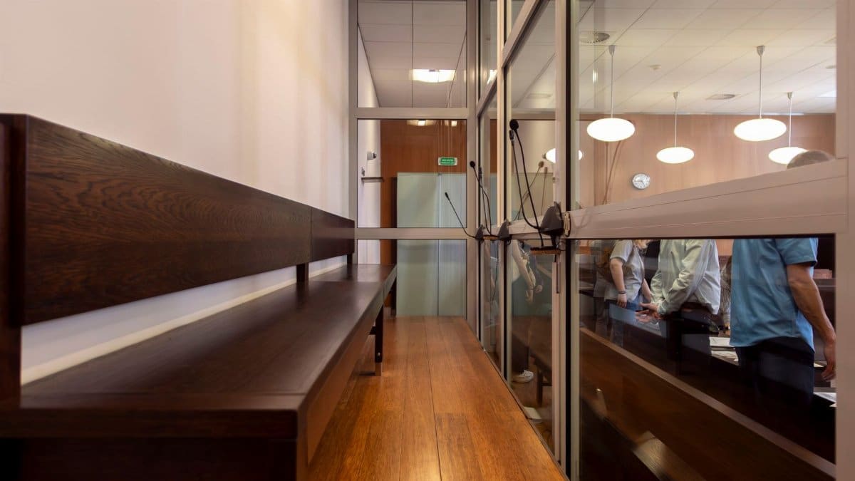 Interior view of a courtroom in Wrocław, Poland, featuring wooden benches and glass partitions.