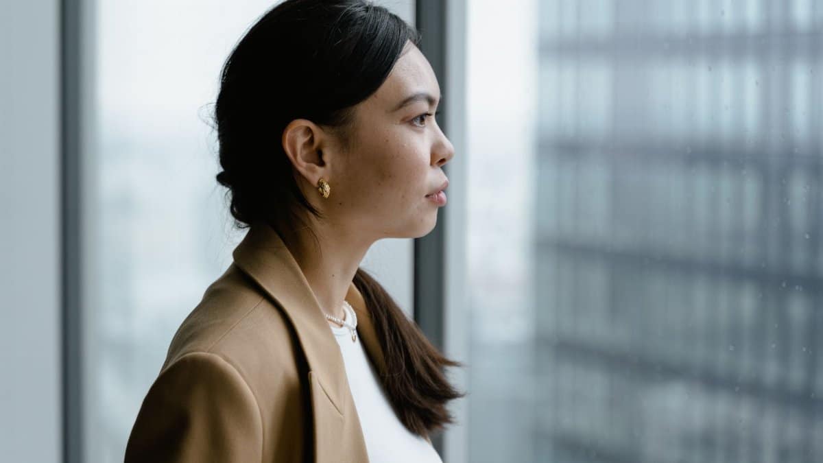 Profile of an Asian woman in a business setting looking thoughtfully out of a window.