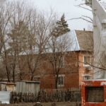 Statue of soldier in Семенной, Russia, surrounded by bare trees and houses.