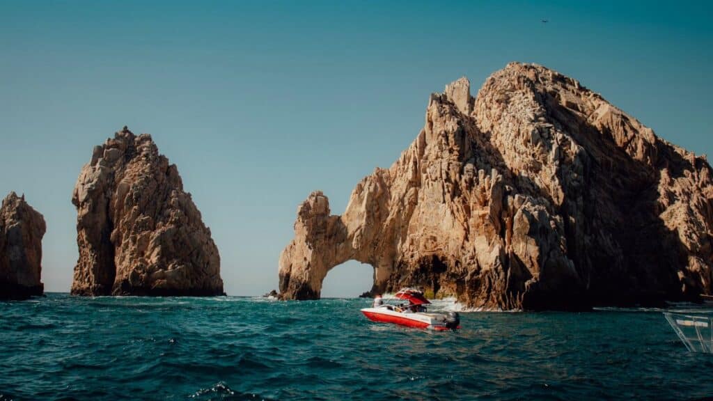 Explore the iconic El Arco rock formations in Cabo San Lucas with a boat navigating the blue Pacific waters.