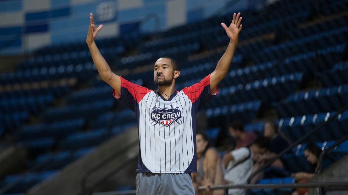 Referee signals during a basketball game at an indoor stadium wearing sports attire. Action capture.