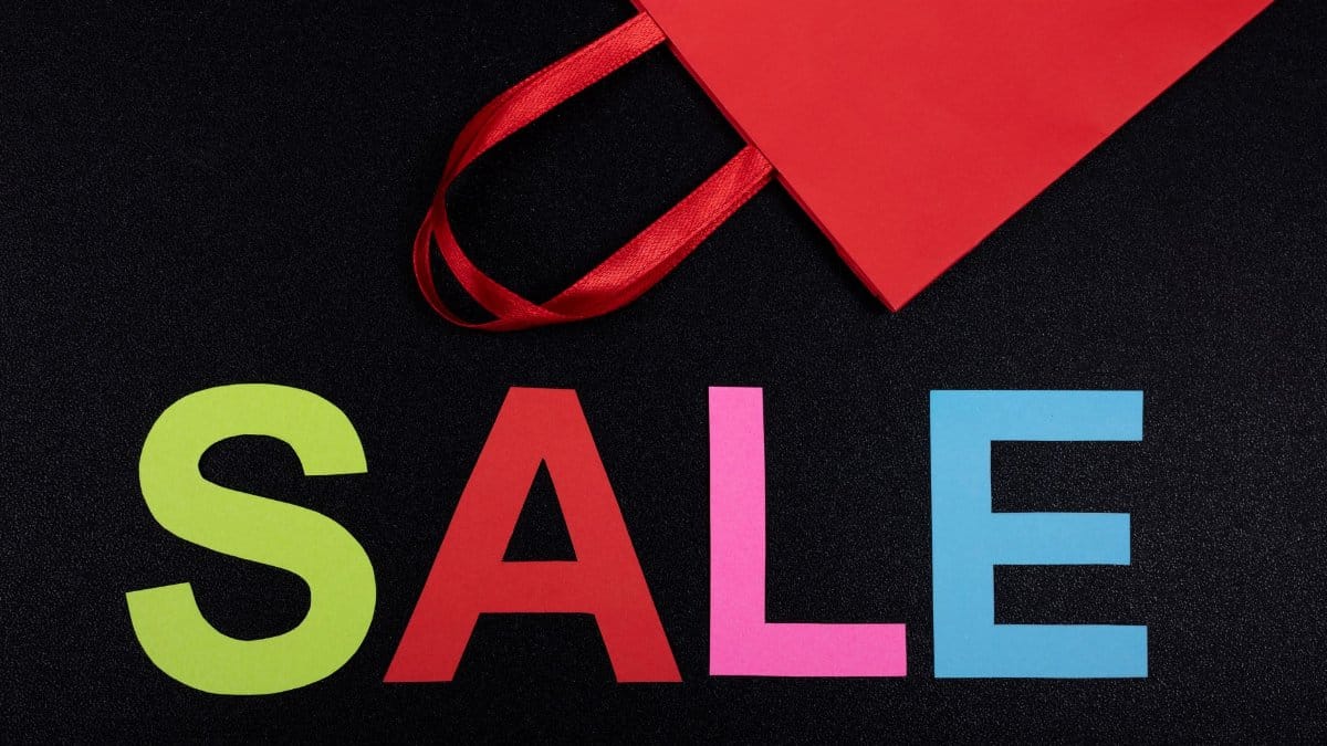 Vibrant text 'SALE' next to a red paper bag on a black background.