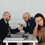 Two lawyers discuss documents with a worried client in a professional office setting.