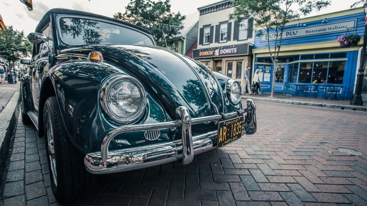 A classic green vintage car parked on a quaint brick street in Annapolis, Maryland.