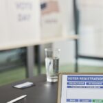 Tablet displaying digital voter registration at indoor voting station with vote day signs.