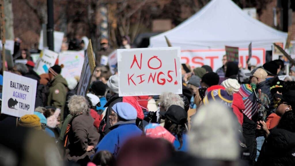Crowd in Baltimore protesting leadership with signs like 'No Kings'.