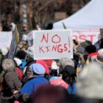 Crowd in Baltimore protesting leadership with signs like 'No Kings'.