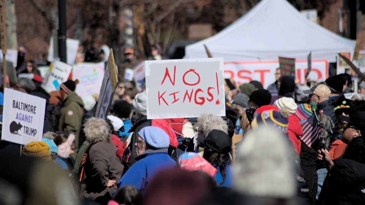 Crowd in Baltimore protesting leadership with signs like 'No Kings'.