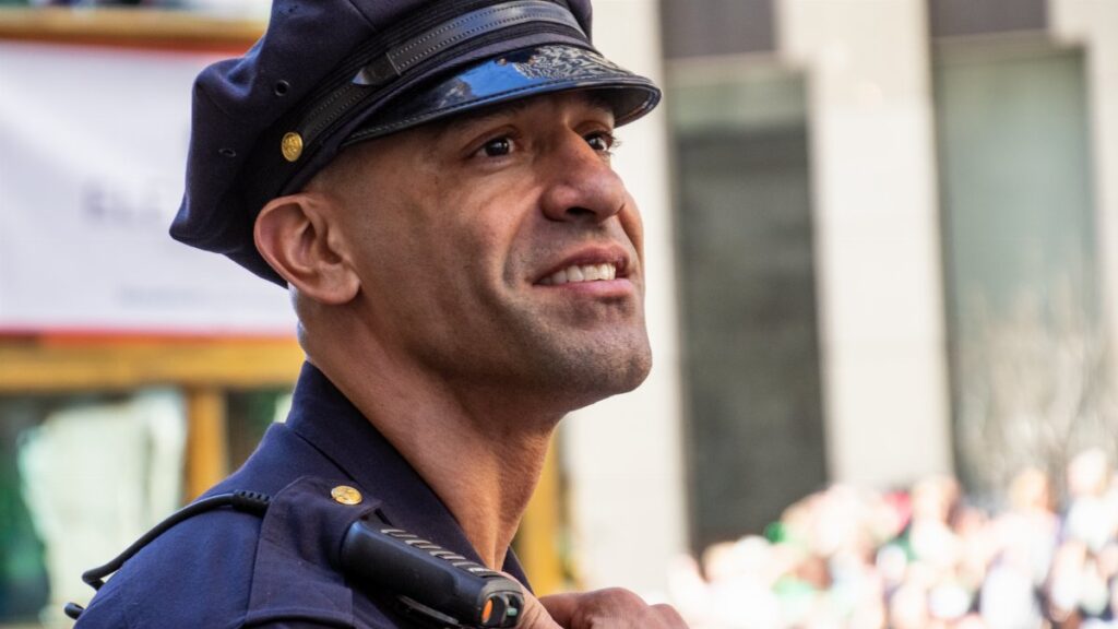 A San Francisco police officer in uniform smiling during an outdoor event.