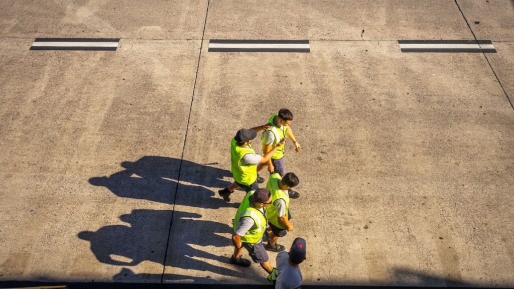Aerial view of airport workers walking on the tarmac in Buenos Aires on a sunny day.