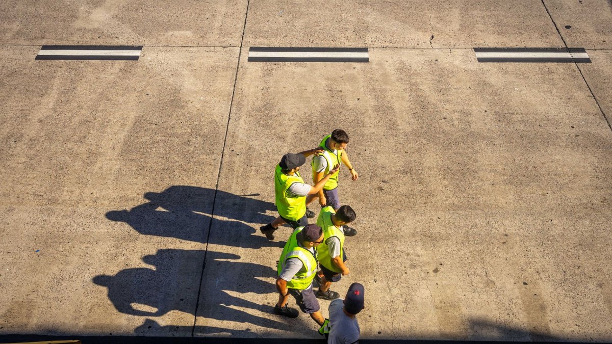 Aerial view of airport workers walking on the tarmac in Buenos Aires on a sunny day.