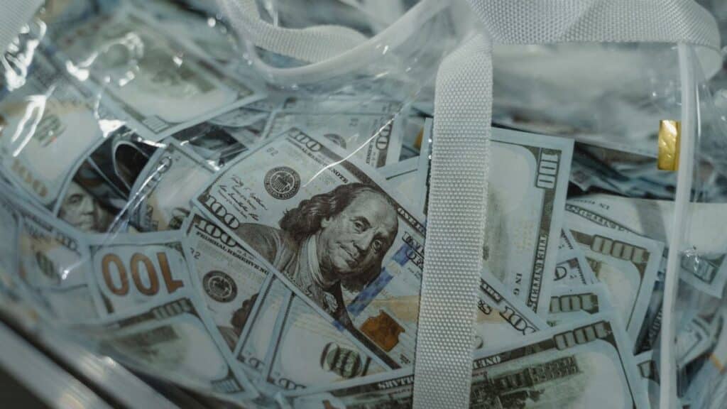 Close-up of transparent bag containing hundred dollar bills, symbolizing wealth.