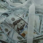 Close-up of transparent bag containing hundred dollar bills, symbolizing wealth.