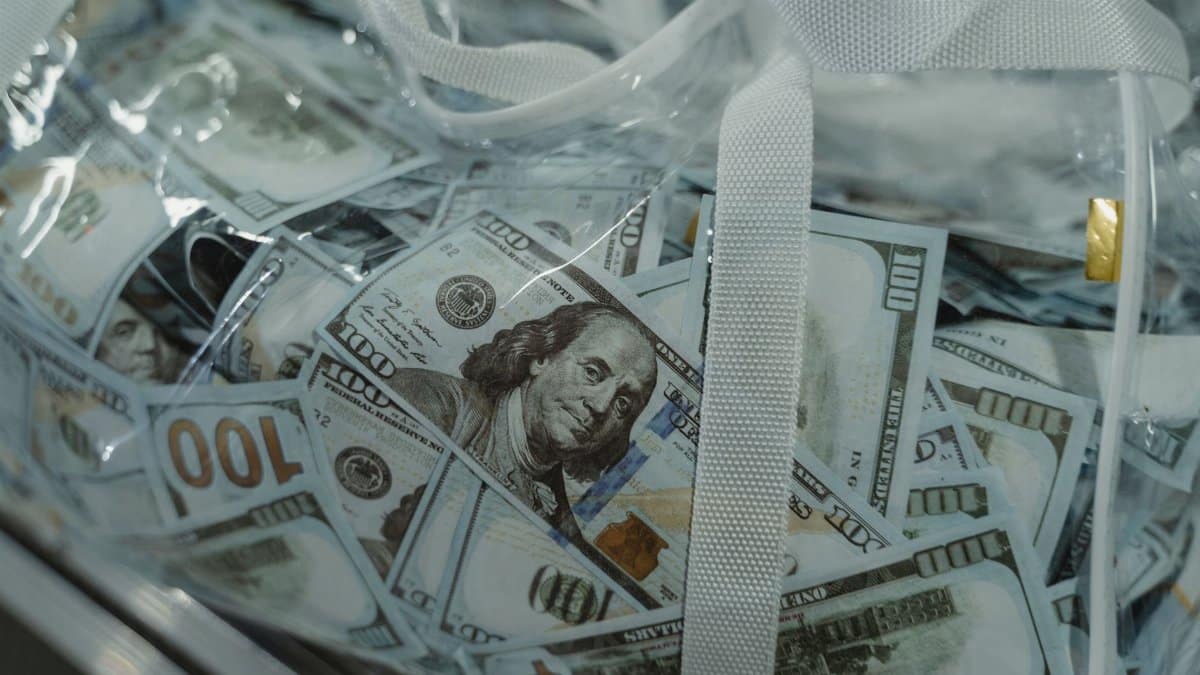 Close-up of transparent bag containing hundred dollar bills, symbolizing wealth.