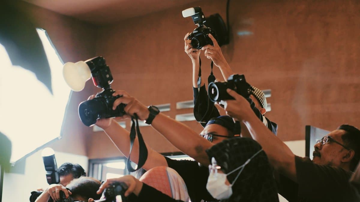 A dynamic gathering of photographers capturing moments indoors with flash.