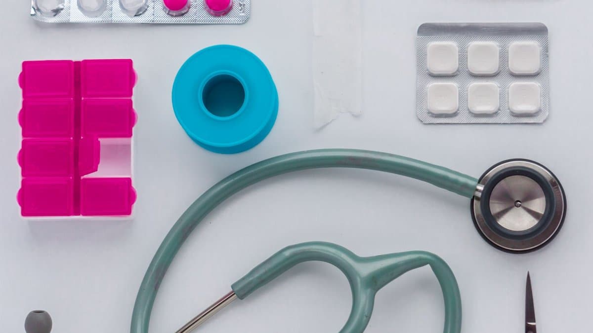 Top view of medical tools, pills, and equipment arranged on a white background, conveying healthcare essentials.