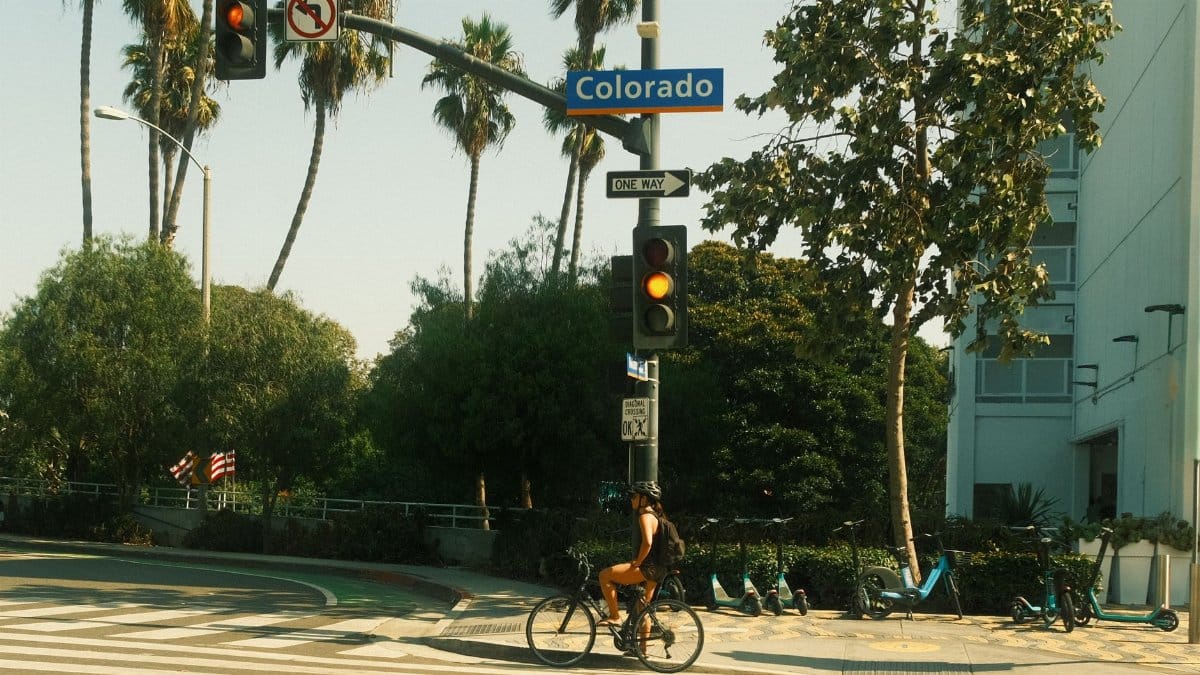 Bicyclist waits at traffic light on Colorado Street in sunny Los Angeles.