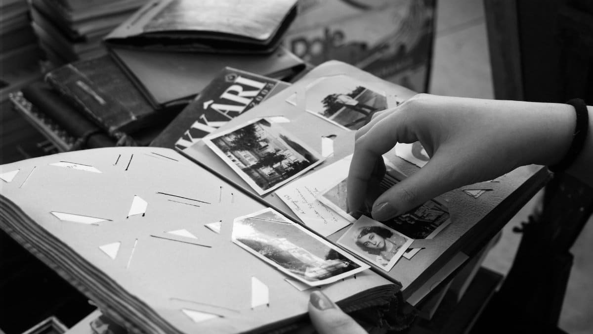 A person browsing an old photo album filled with black and white memories.