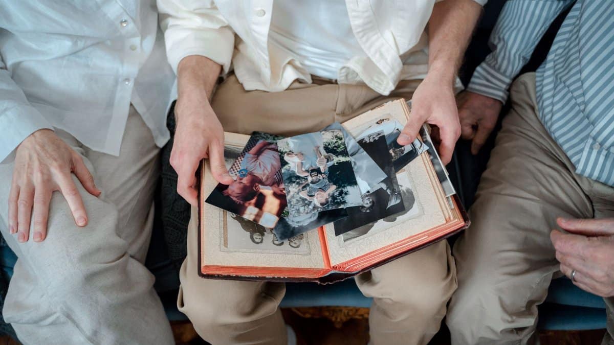 A family of three enjoying old photos together, sharing cherished memories.