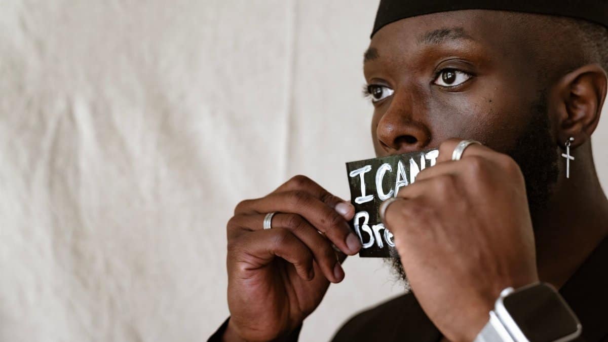 Man holding 'I Can't Breathe' sign in protest, highlighting social issues.