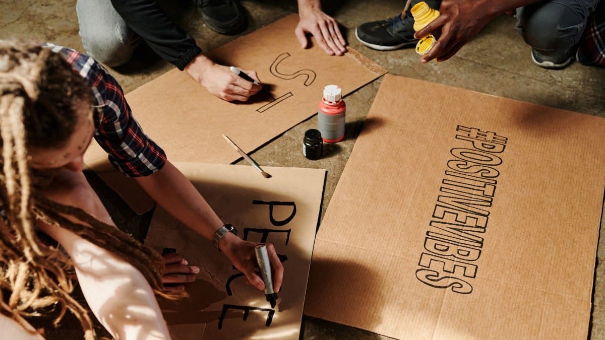 A diverse group crafting protest signs with positive messages. Engaged activism captured creatively.