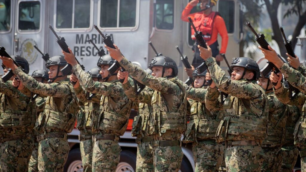 Mexican soldiers in camouflage uniforms raise weapons during a military parade in Colima, Mexico.
